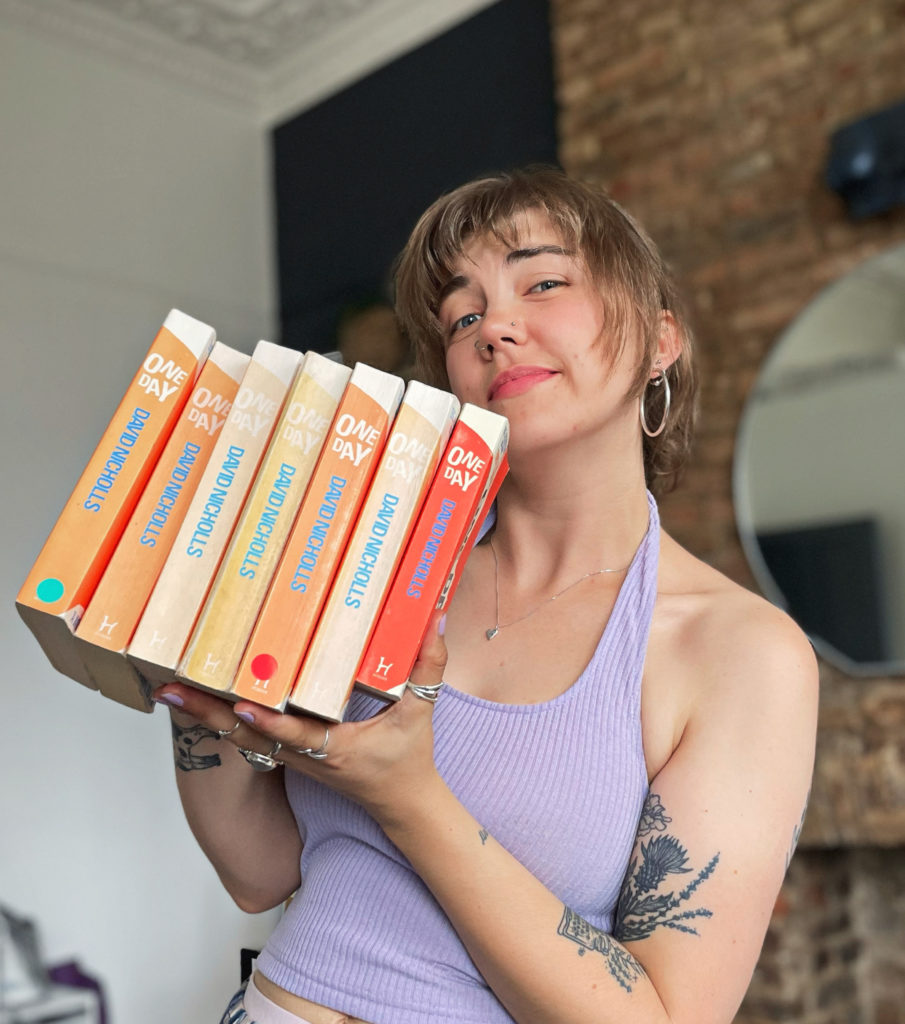 Grace proudly holding her many copies of One Day, the novel by David Nicholls, and raising an eyebrow to the camera.