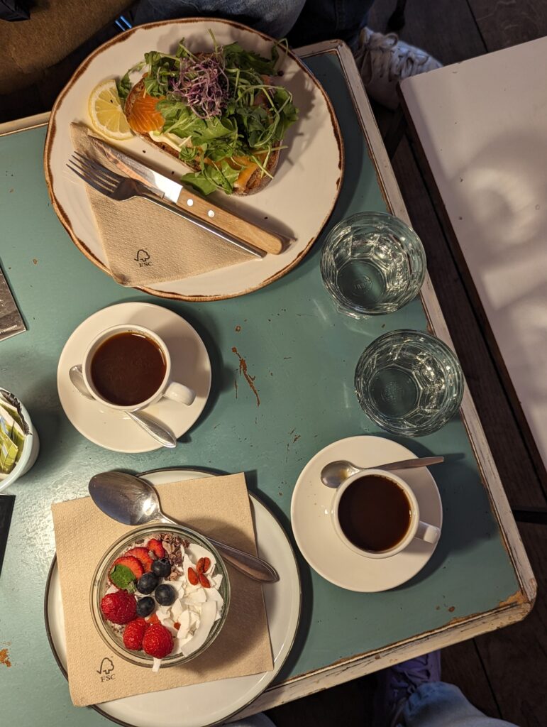 two coffees and two breakfasts on a cute teal table.