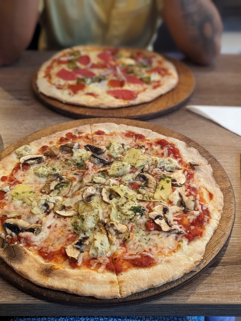 Amsterdam Pizzas x2 on a table (one vegan, one not)